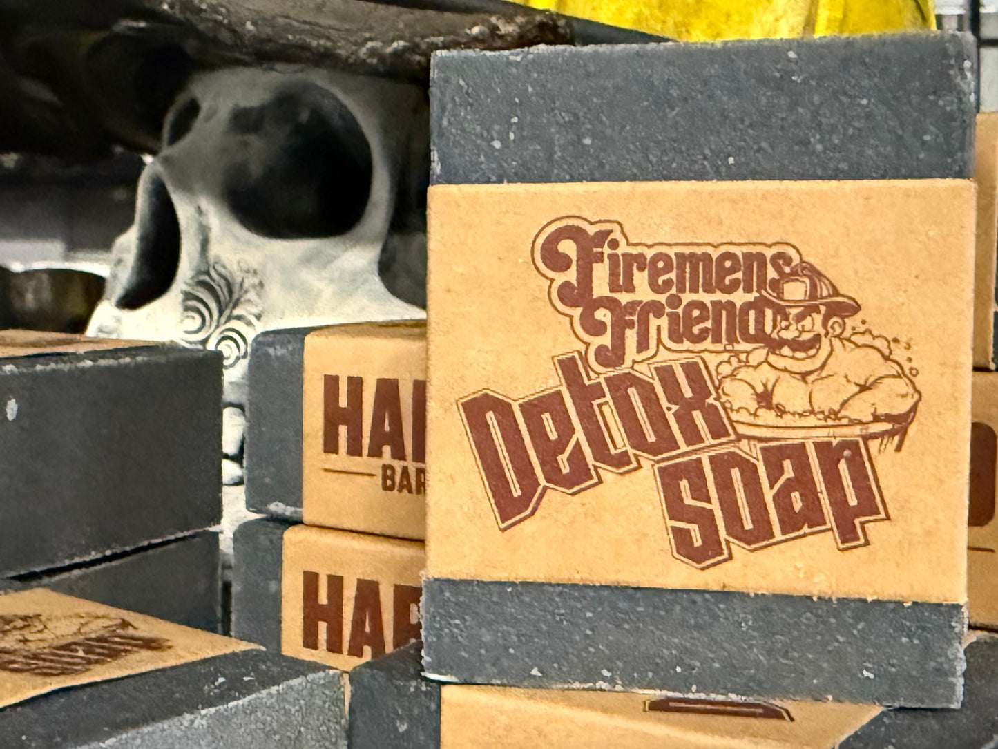 Stack of 'Firemen's Friend Detox Soap' bars with cardboard packaging in a warehouse setting.